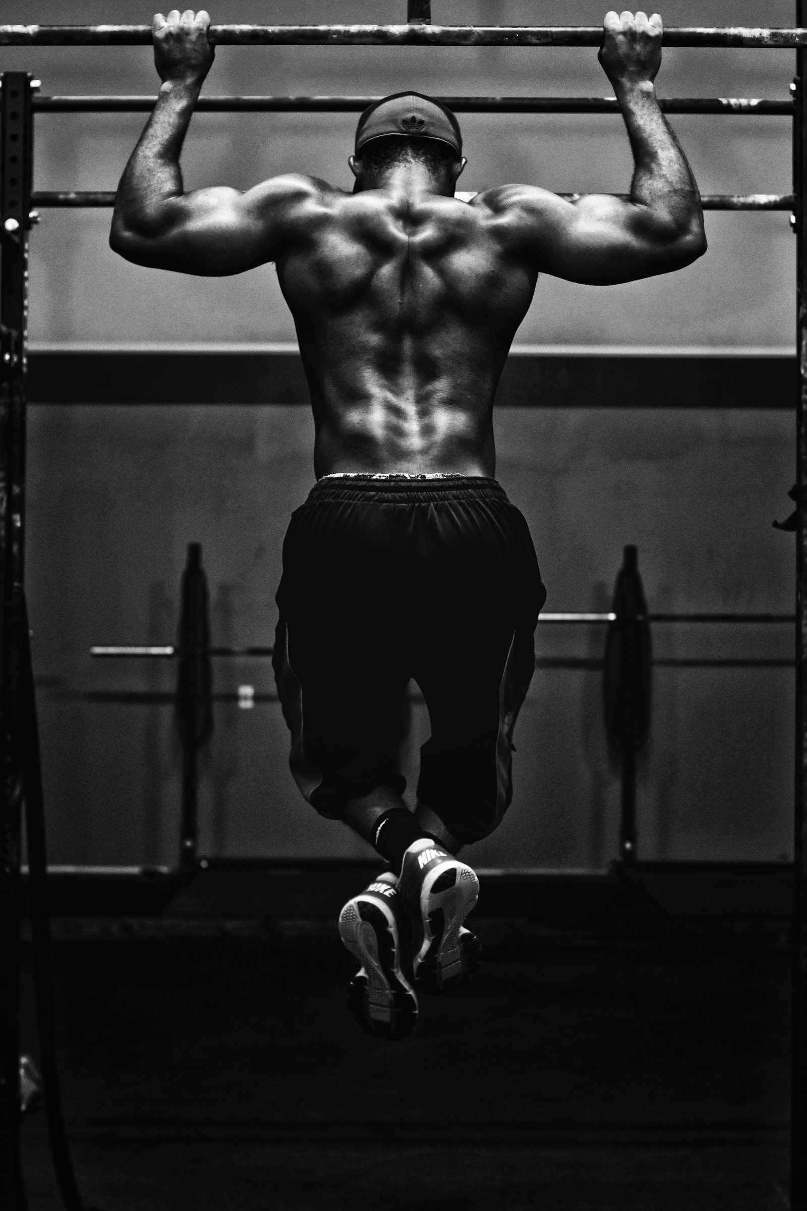 Atleta haciendo una dominada en un espacio de entrenamiento oscuro.